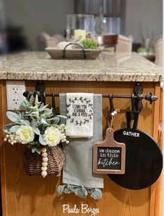 a kitchen counter with towels hanging from hooks and flowers in a basket on the towel rack