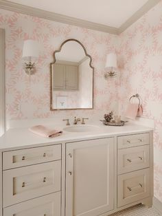 a bathroom with pink and white wallpaper, two sinks and a mirror on the wall