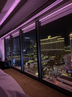 a bedroom with a view of the city lights at night from it's windows