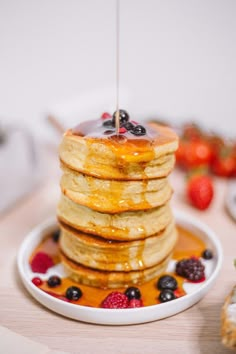 pancakes stacked on top of each other with syrup and berries in the foreground text reads, ma recette des fluffy pancakes