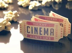 two tickets sitting on top of a table next to popcorn