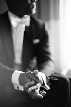 a man in a tuxedo holding another mans hand