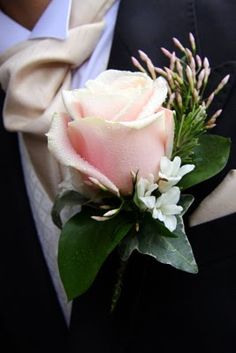 a boutonniere with pink roses and white flowers