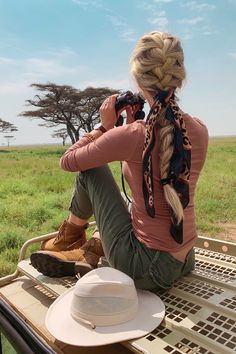 a woman sitting on the back of a vehicle while taking a photo with her camera