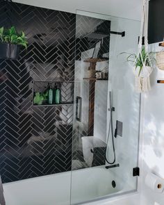 a bathroom with black and white tiles on the wall, shower head, and shelves