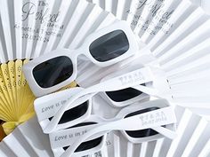 several pairs of white sunglasses sitting on top of each other next to a fan with love is in the air written on it