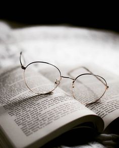 an open book with glasses on top of it