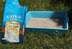 a bag of cat litter sitting next to a blue box on the grass with it's lid open