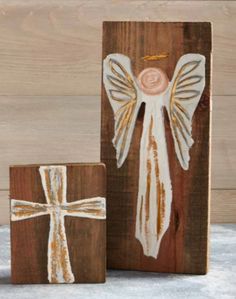 two wooden blocks with an angel and cross painted on the front, one in white