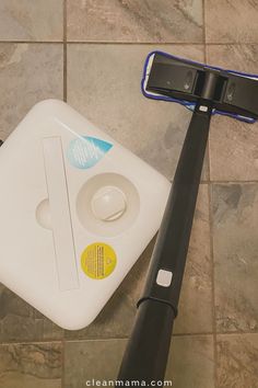 a floor scruber sitting on top of a tile floor next to a cleaning brush