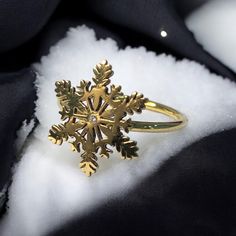 a gold snowflake ring sitting on top of white fabric