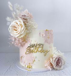 a birthday cake decorated with flowers and the words happy birthday written on it in gold lettering