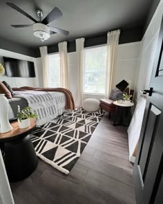 a bed room with a neatly made bed next to a window and a ceiling fan