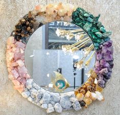 a circular mirror with various rocks and stones around it on a wall next to a chandelier