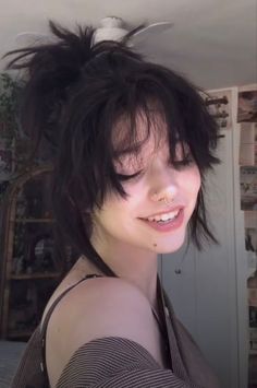 a young woman with black hair and piercings on her nose smiles at the camera