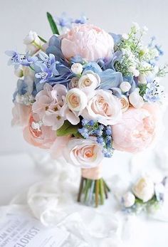 a bouquet of flowers sitting on top of a white table next to an open book