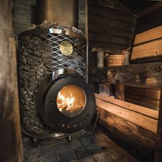 a wood burning stove sitting inside of a log cabin next to wooden planks and logs