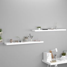 two white shelves with plants on them against a gray wall