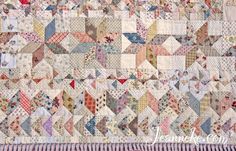 an old quilt with many different colors and patterns on the front, along with a pink stripe