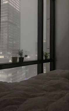 a bed sitting next to a window with a view of the city in the distance