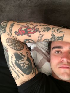 a man with tattoos on his arms and shoulder is laying down in front of the camera