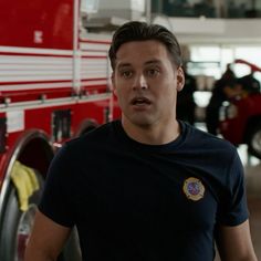 a man standing in front of a firetruck with his hand on his hip