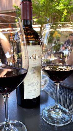 two glasses of wine sitting on top of a table next to a bottle of wine