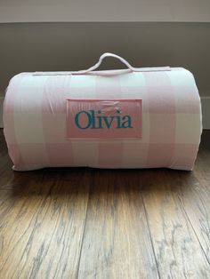 a pink and white checkered duffel bag with the name oliva on it