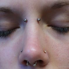 a close up of a person's nose with piercings on their nose and eyes