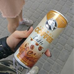 a person holding a can of coffee in their hand