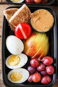 two black trays filled with different types of food