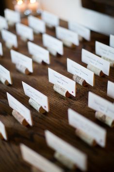 place cards are placed on a wooden table with candles in the backgroung