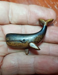 a hand holding a tiny toy whale in it's palm