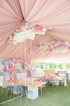 a party tent with tables and chairs covered in balloons