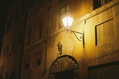 a street light on the side of an old building at night with no one in it