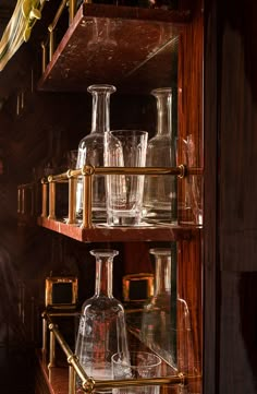 several glass bottles and glasses on shelves in a room