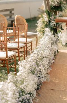 the chairs are lined up on the side of the road with flowers growing along them