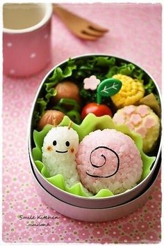 some food in a metal container on a table with a pink cup and utensils