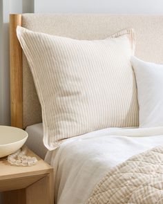 a bed with two pillows on top of it and a bowl sitting next to it