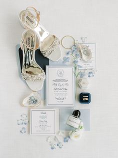 the wedding stationery is laid out with shoes, rings, and other things to include