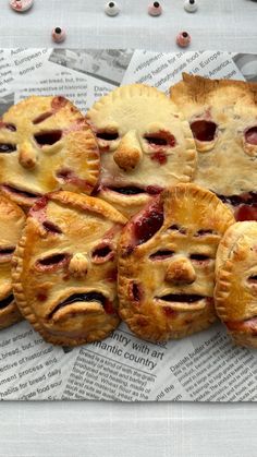 several pies with faces drawn on them sitting on top of newspaper paper next to each other