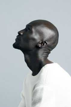 a man with black hair and white shirt looking up at something in the air on his head