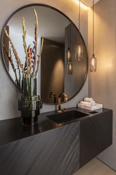 a bathroom with a large round mirror above the sink and lights hanging from the ceiling