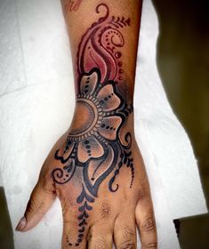 a woman's hand with a tattoo design on the top of her left arm