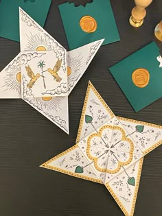 some paper decorations are on a table with gold and green items around them, including one folded origami star