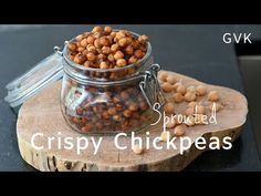 a glass jar filled with chickpeas sitting on top of a wooden board next to a