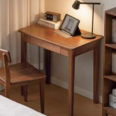 a wooden desk with a lamp on top of it next to a book shelf and chair