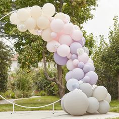 a bunch of balloons that are on top of each other in front of a tree