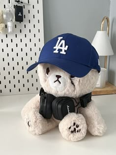 a white teddy bear wearing a baseball cap and holding a pair of black camera's