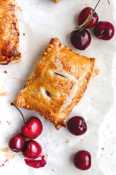 some cherries are laying next to a piece of pie